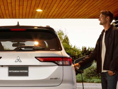 2024 Mitsubishi Outlander PHEV view of man charging vehicle
